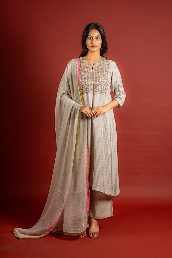 Beige silk top with self-woven butta detailing, with panel and a yoke heavy thread work and sequin embellishments, chiffon dupatta with work and colourful lace detailing, and rayon pant