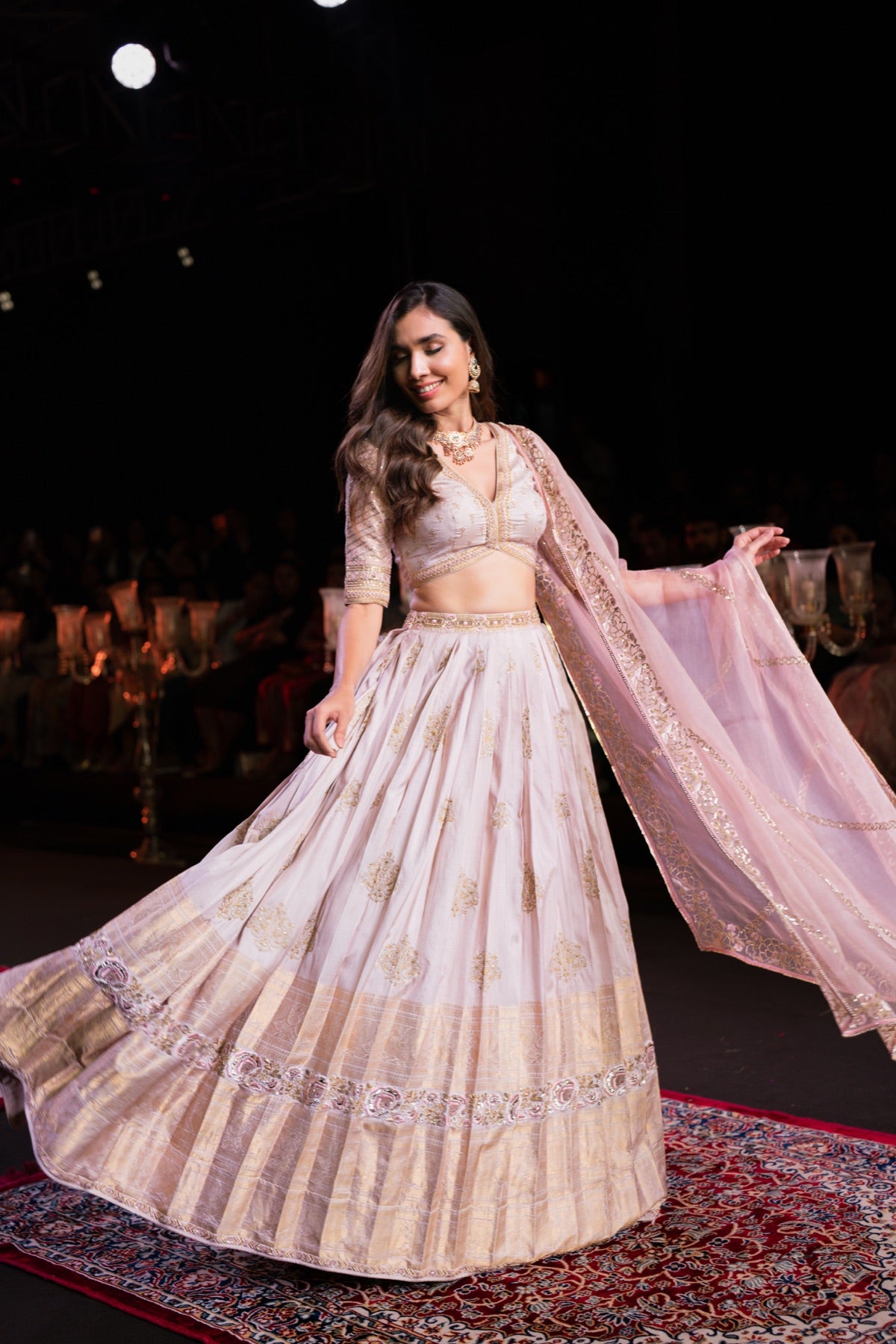 Model in a blush lehenga, mid-movement
