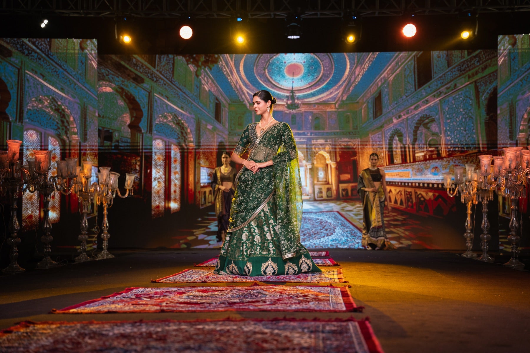 Model in an emerald lehenga against a palace projection backdrop
