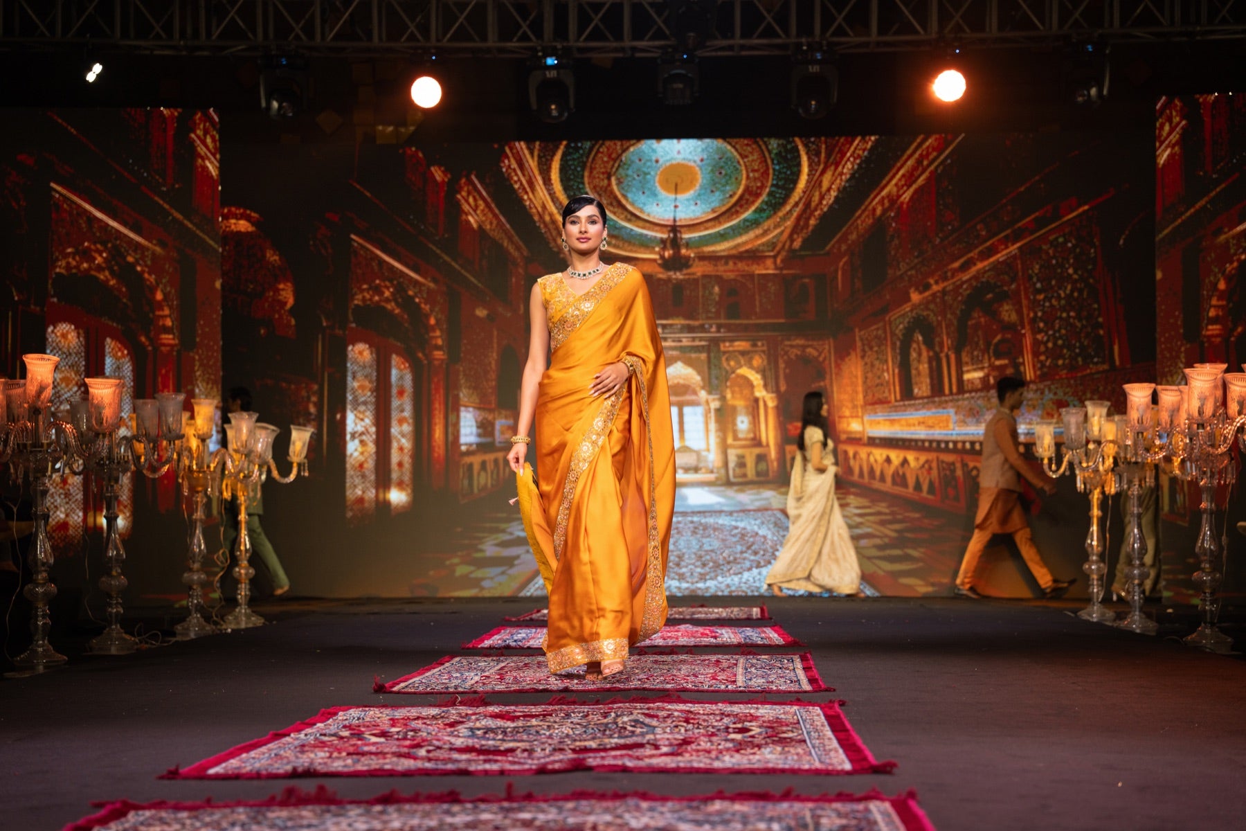 Model in a mustard saree against an ornate backdrop