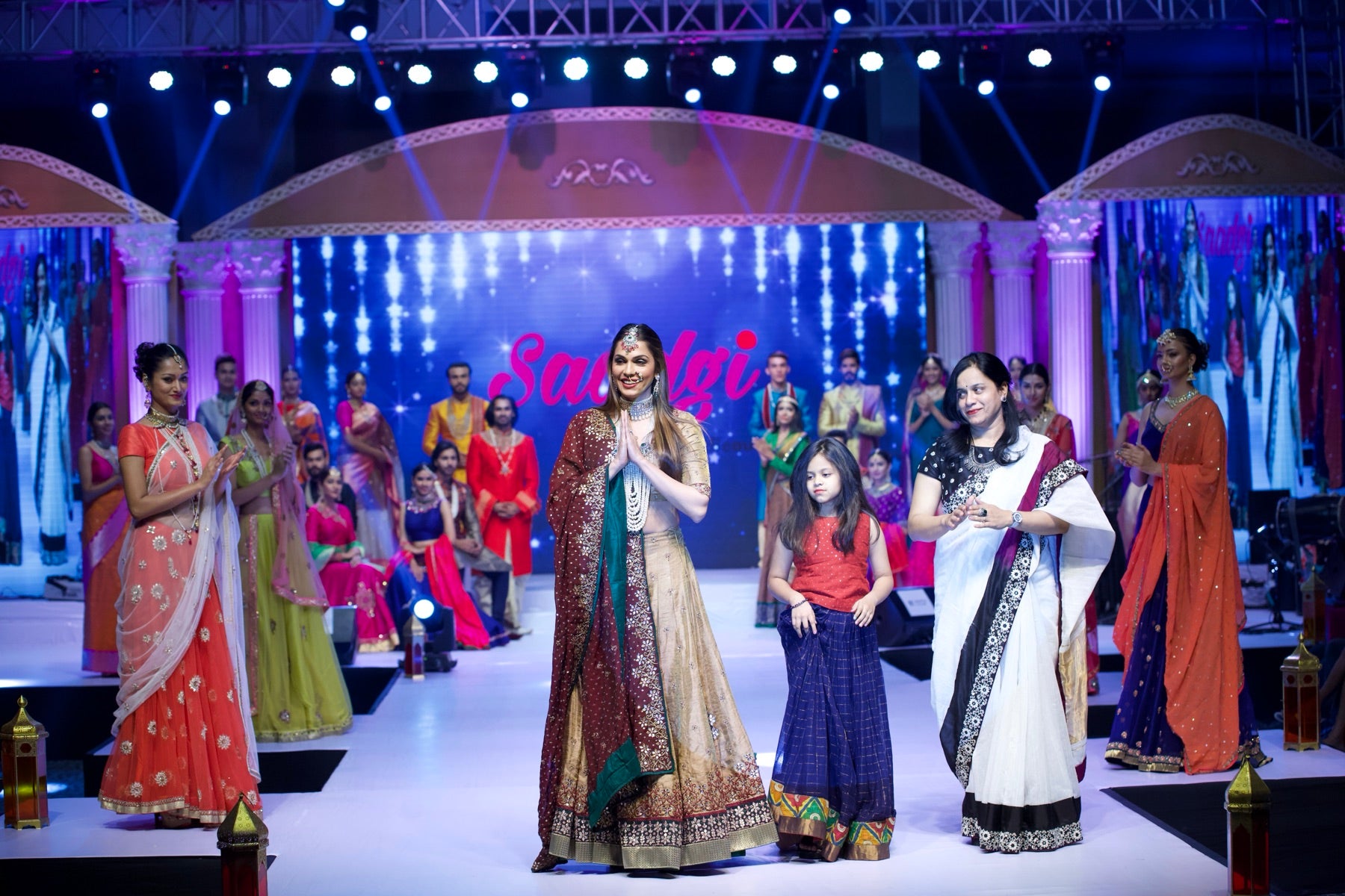 Models on stage in colorful sarees beneath the Saadgi backdrop