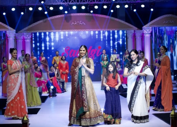 Designer greeting the audience on stage with a child and guest at the Saadgi show